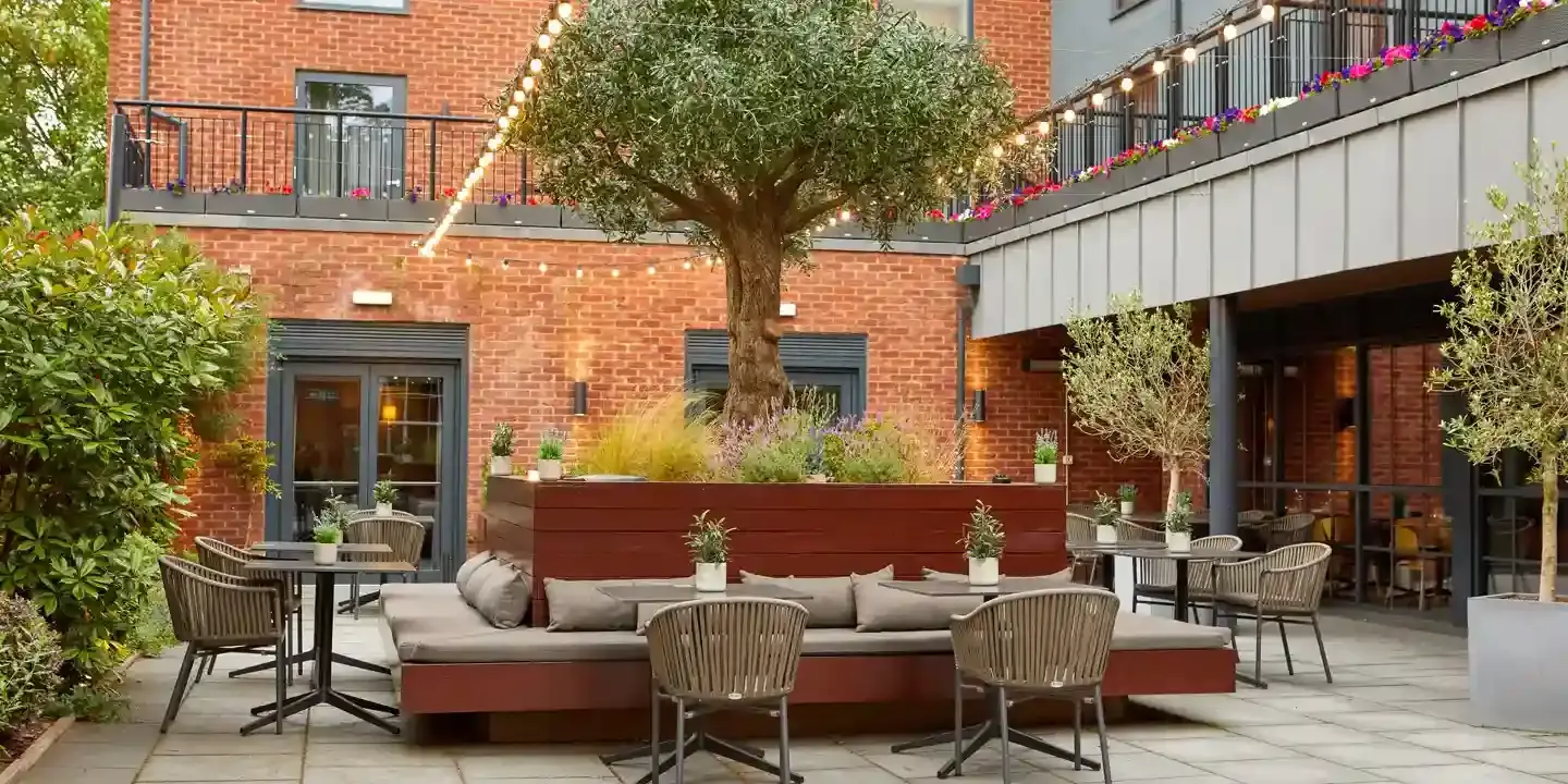 A patio featuring tables, chairs, and a large centre tree.