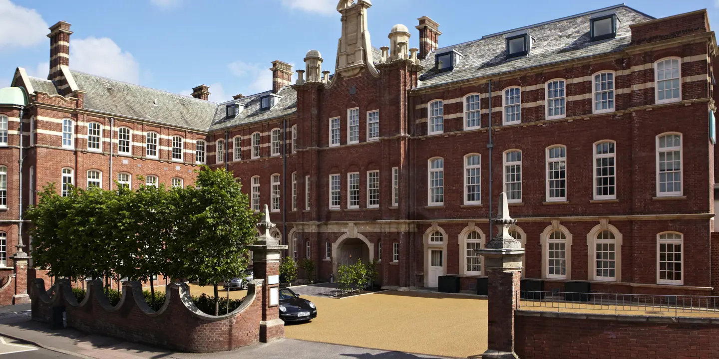 An imposing brick building featuring a brown stoned driveway.