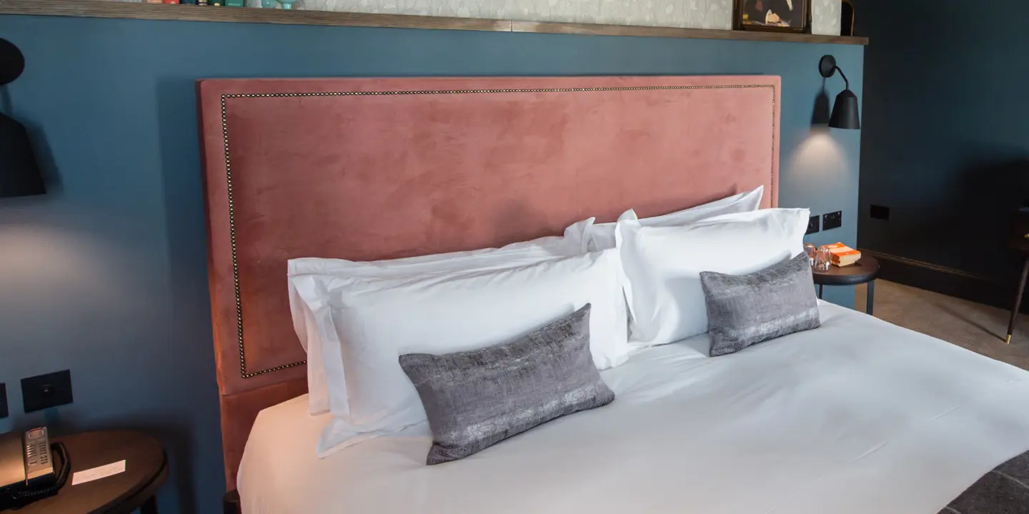 A bed with two pillows and a pink headboard