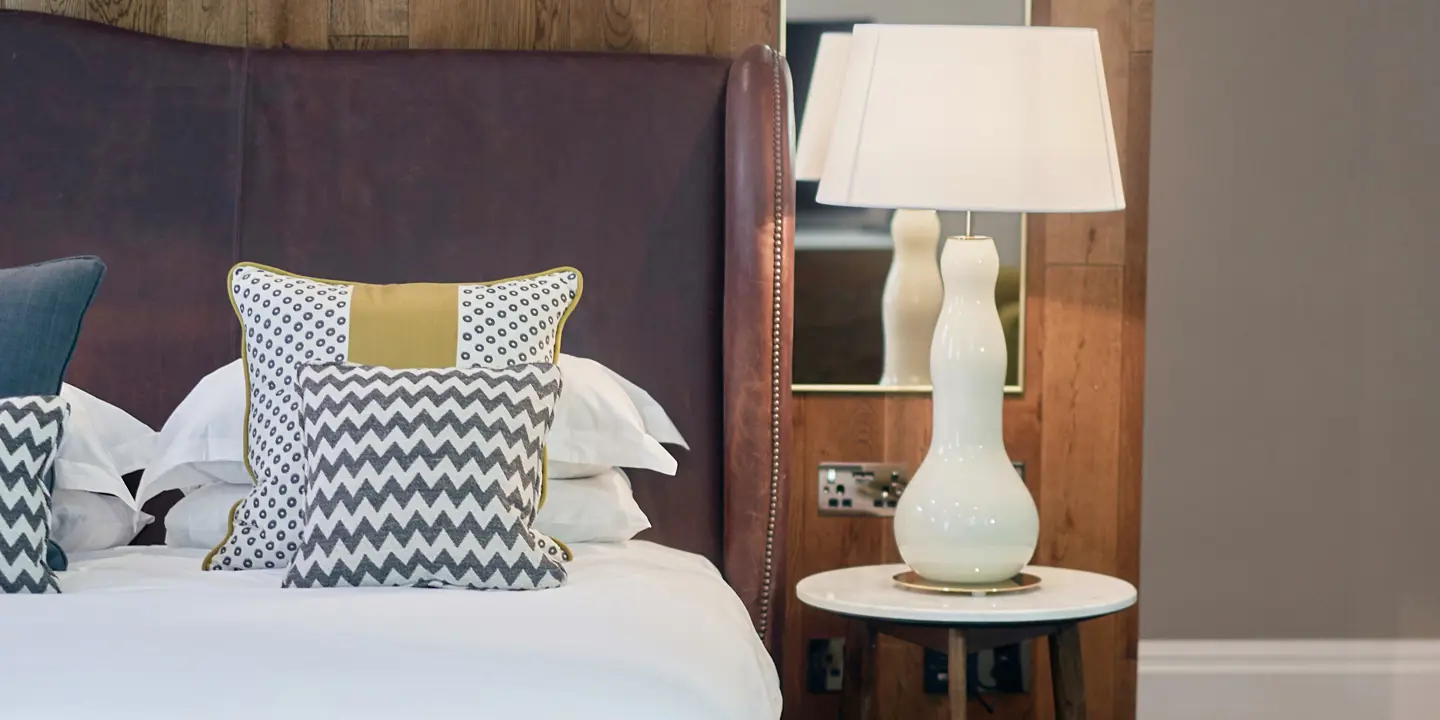 A brown leather bed with white sheets and matching pillows