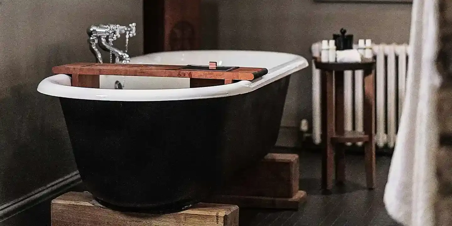 Black bathtub and wooden stand in a bathroom.