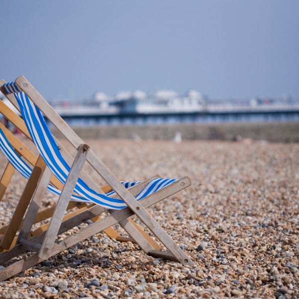 A beach chair resting on a rocky shoreline.