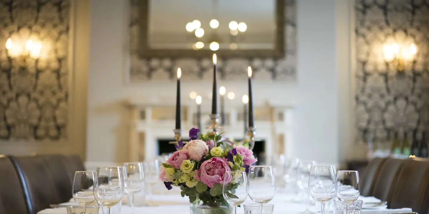 Table elegantly set for a formal dinner, adorned with candles and flowers.