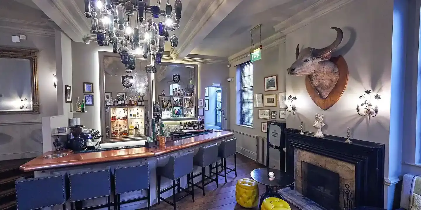 A bar with numerous chairs and a cozy fireplace.