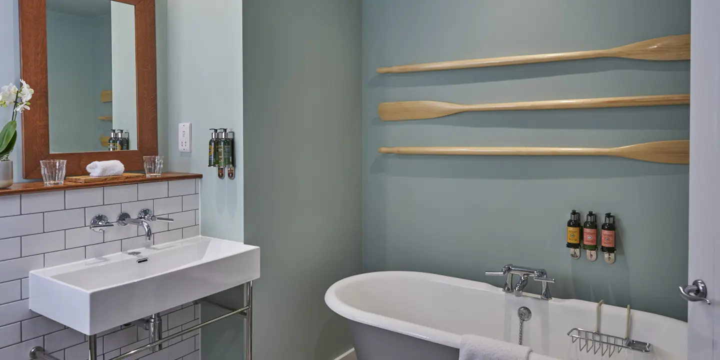 Bathroom featuring a bathtub, sink, mirror and 3 wall mounted wooden oars.