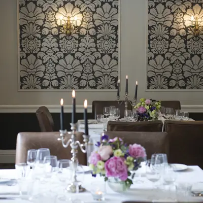 Table elegantly set for a formal dinner, adorned with candles and flowers.