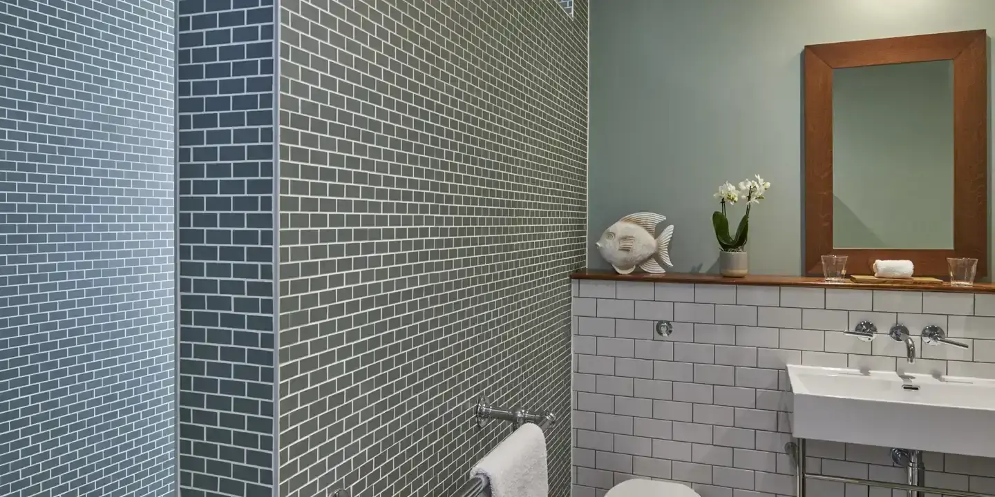 A bathroom featuring a toilet, sink, mirror and fish ornament.