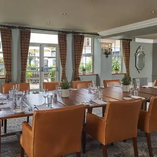 A high ceilinged dining room featuring a spacious table and leather chairs.