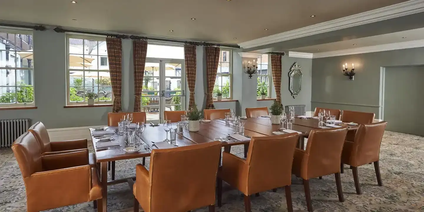 A high ceilinged dining room featuring a spacious table and leather chairs.