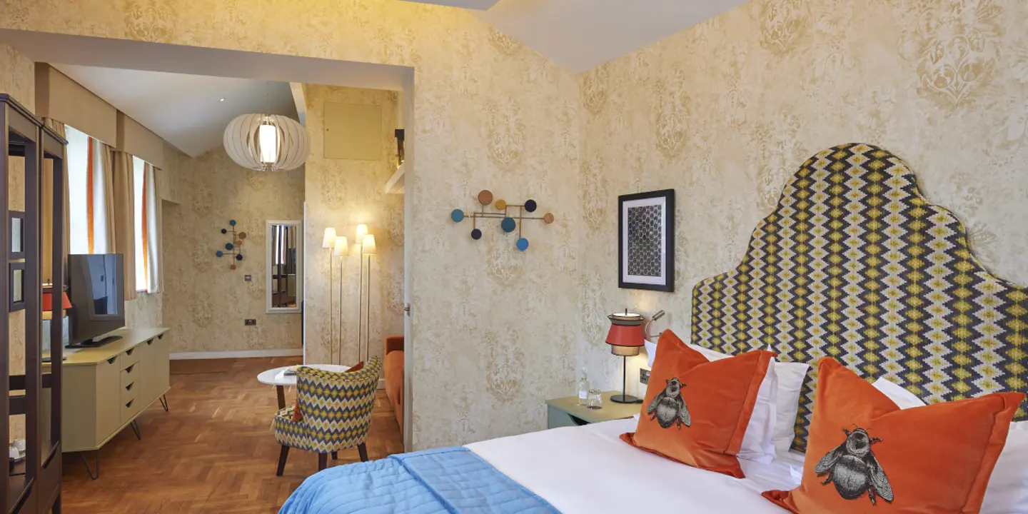 An elegantly furnished hotel room featuring a comfortable bed, sofa and a functional desk.
