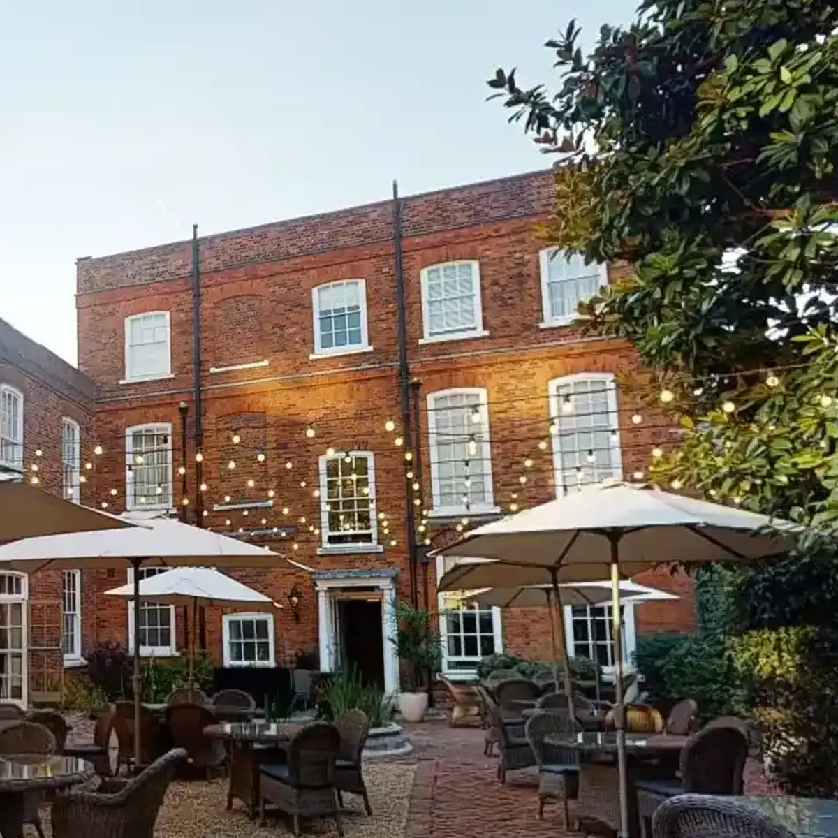 A courtyard featuring tables, chairs, and umbrellas.