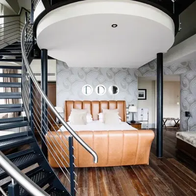 Bedroom featuring a comfortable bed and an elegant spiral staircase.