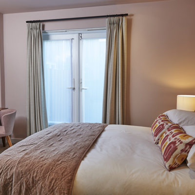 Bedroom featuring a comfortable bed, desk, and opening glass door.