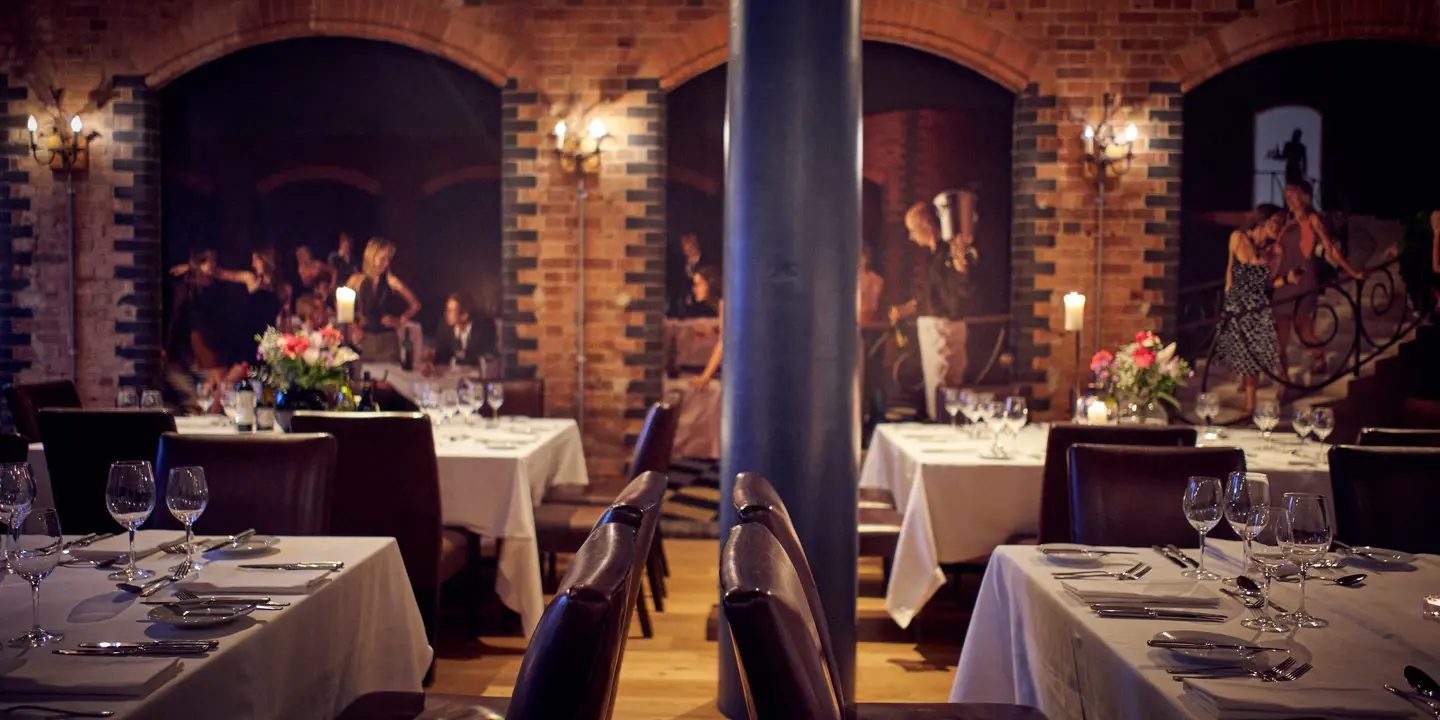 A restaurant arranged with neatly set tables and chairs for an evening meal.