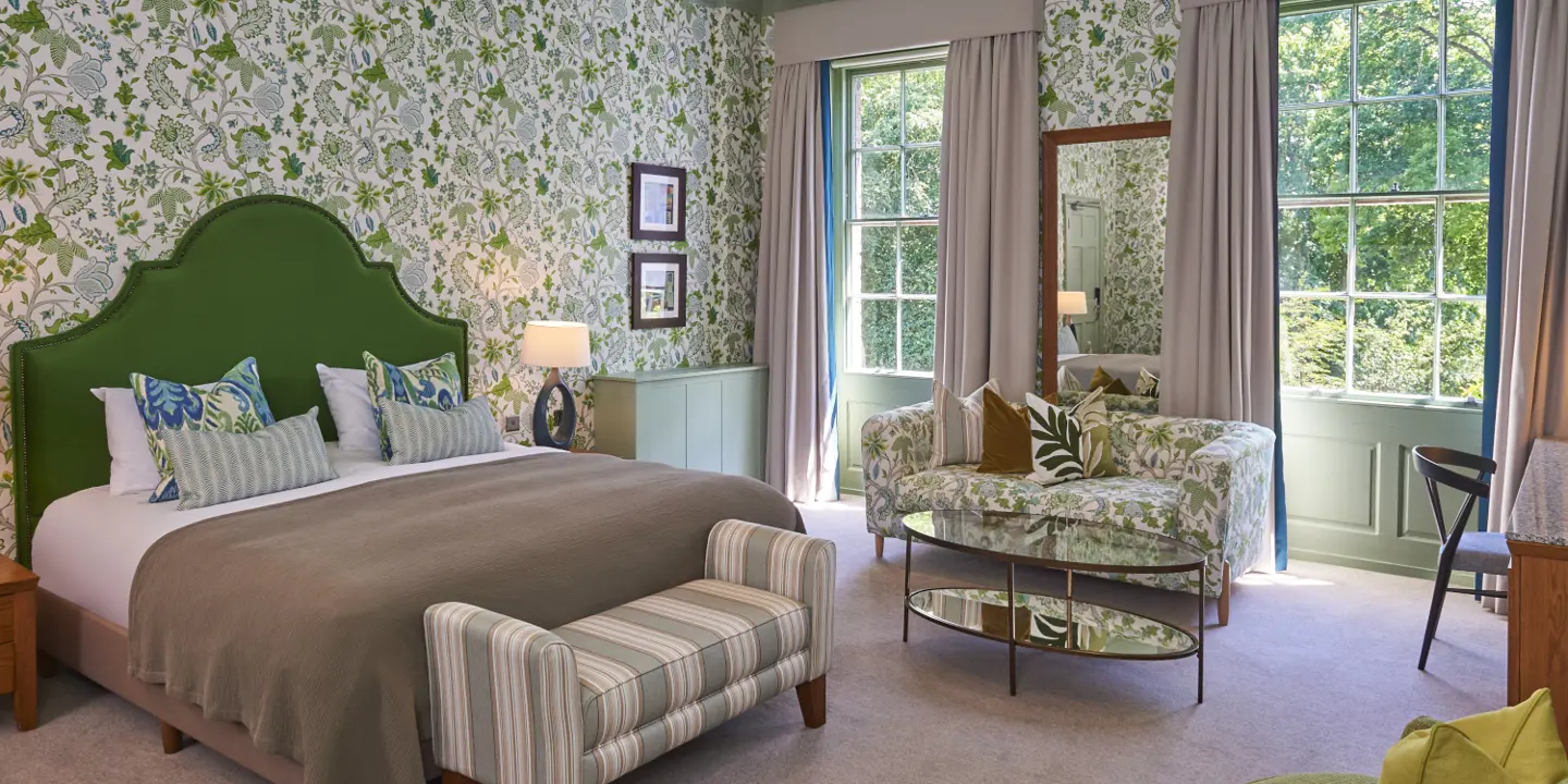 Bedroom featuring a comfortable bed, chairs, and a window.