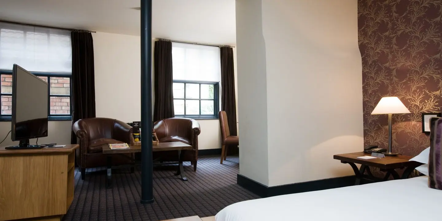 An elegantly furnished hotel room featuring a comfortable bed, spacious desk, and cozy chair.