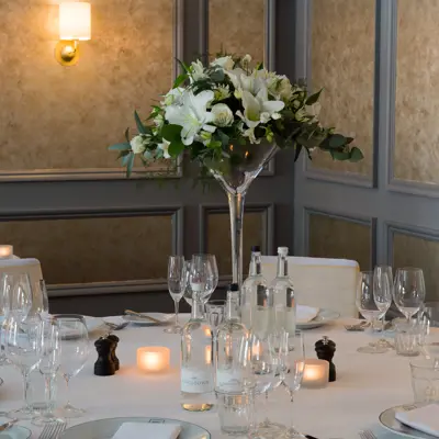 Table elegantly set for a formal dinner, adorned with candles and flowers.