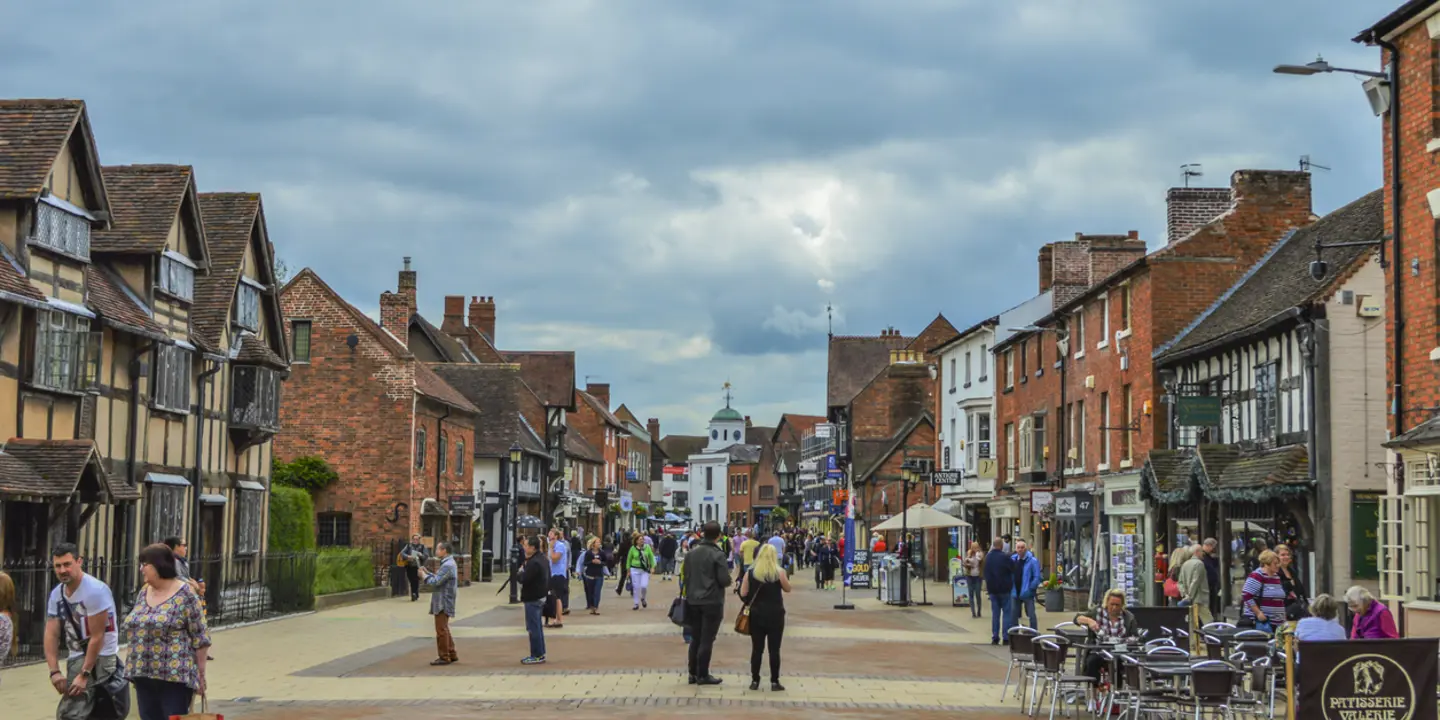 A group of individuals strolling along a town street beside towering buildings.