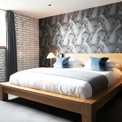 Spacious bedroom featuring a king-sized bed and an exposed brick wall.