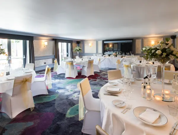 An elegantly decorated banquet room featuring pristine white tables and chairs.