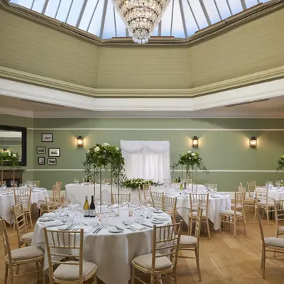 An elegantly decorated banquet room featuring pristine white tables and chairs.