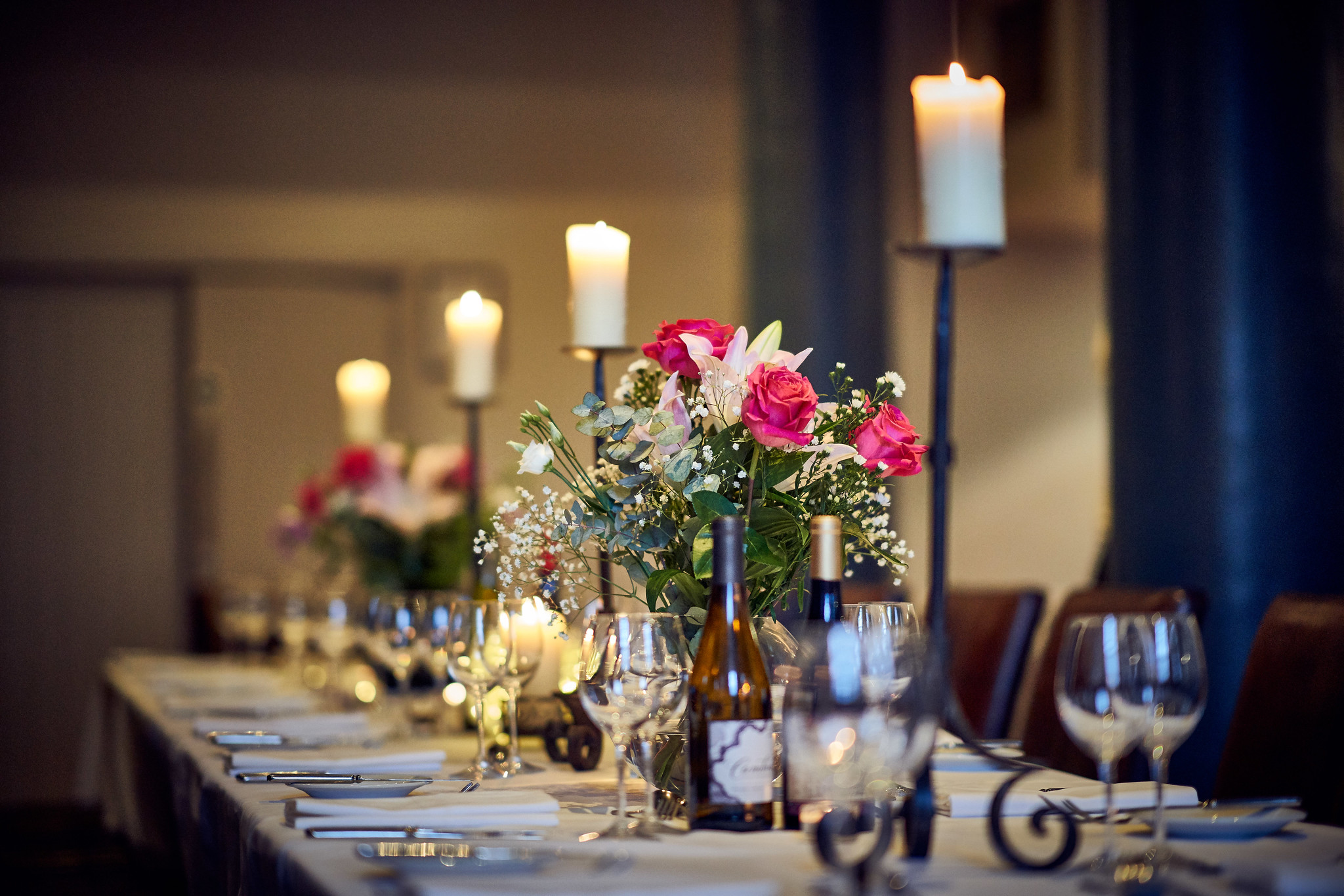 Table elegantly set for a formal dinner, adorned with candles and flowers.