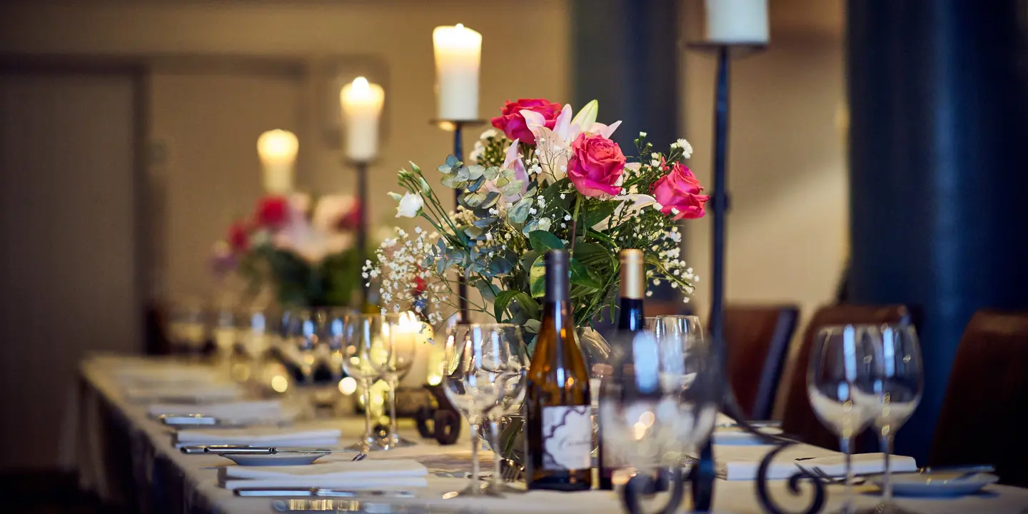 Table elegantly set for a formal dinner, adorned with candles and flowers.