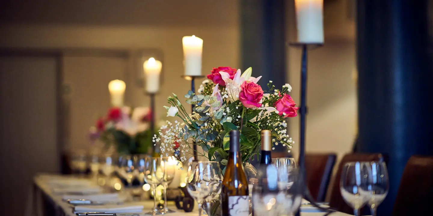 Table elegantly set for a formal dinner, adorned with candles and flowers.