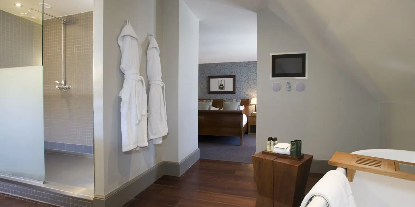 A suite decorated in neutral colours. There is a bed and a modern bathroom in view