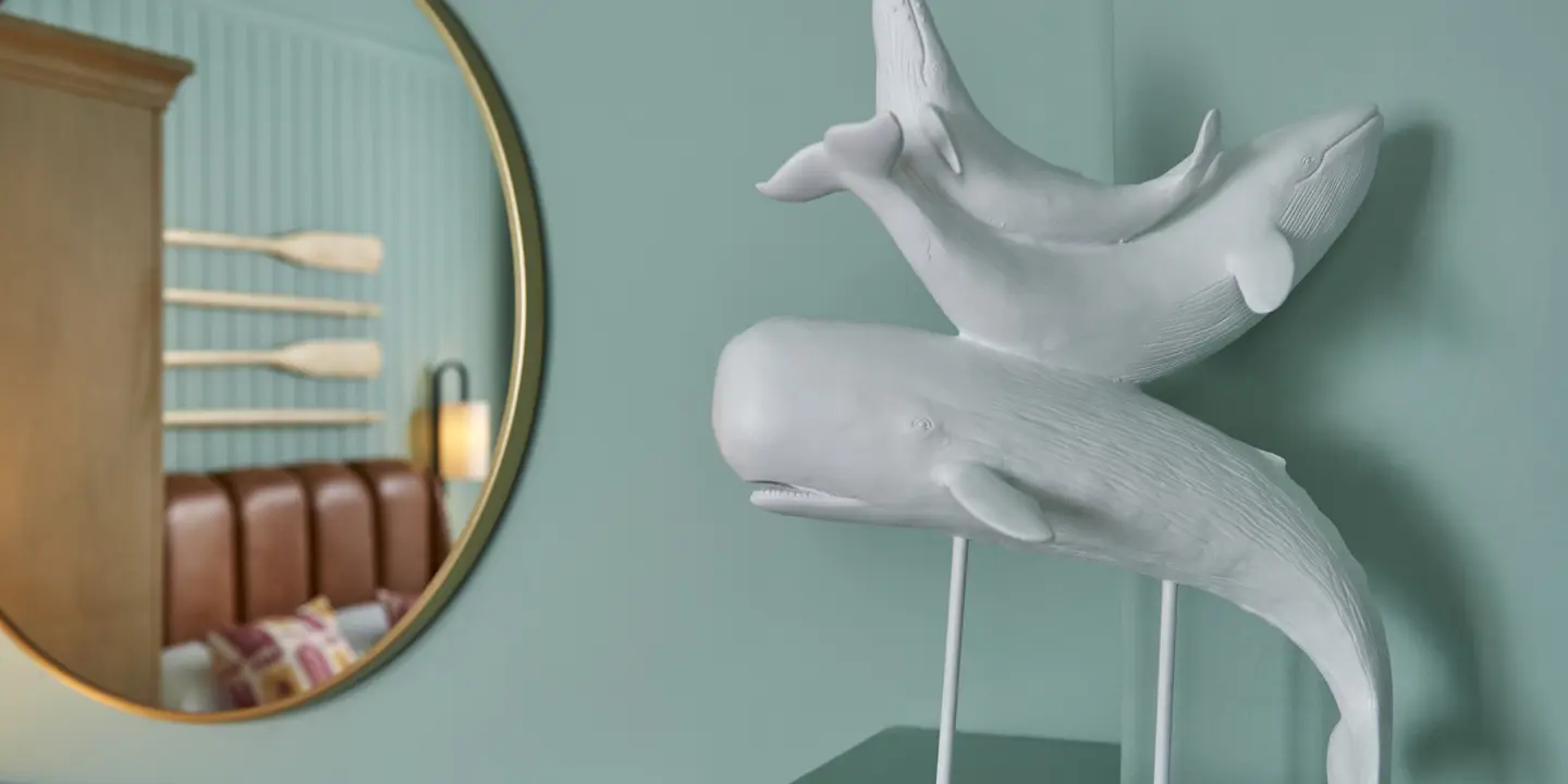 Two whale sculptures displayed on a stand in front of a mirror.